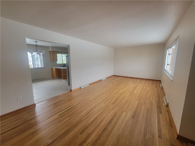 spare room featuring light wood-type flooring and an inviting chandelier