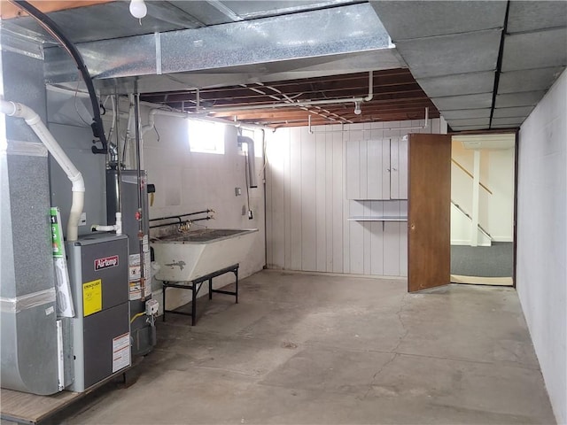 basement featuring heating unit, water heater, and sink