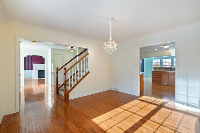 spare room with light hardwood / wood-style floors, an inviting chandelier, and ornamental molding