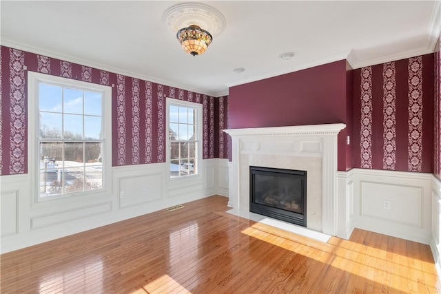 unfurnished living room with a high end fireplace, wood-type flooring, plenty of natural light, and crown molding