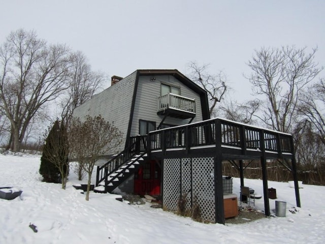 snow covered property featuring a balcony and a wooden deck