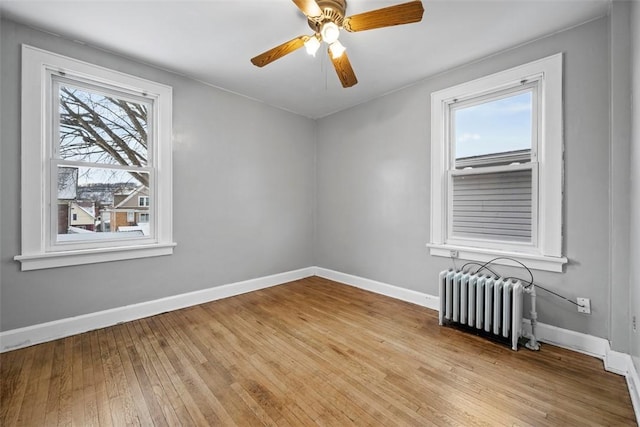 unfurnished room featuring radiator, ceiling fan, a healthy amount of sunlight, and light hardwood / wood-style floors