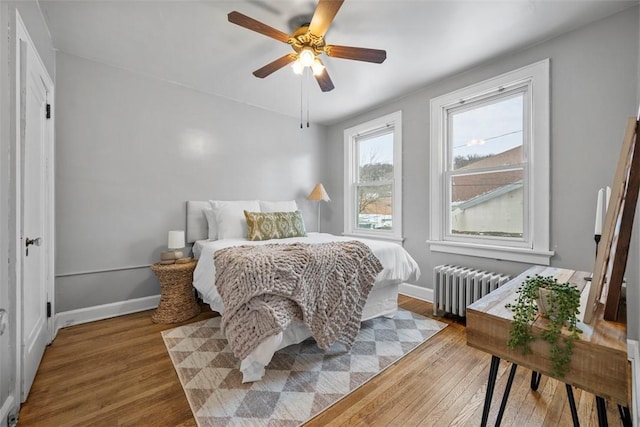 bedroom with ceiling fan, radiator heating unit, and hardwood / wood-style floors