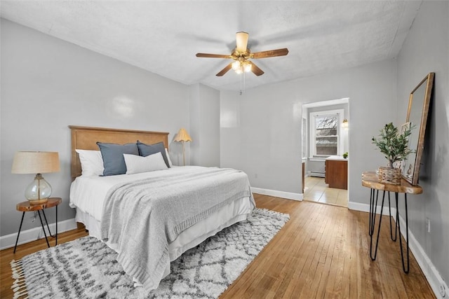 bedroom with ceiling fan, baseboard heating, and light hardwood / wood-style flooring