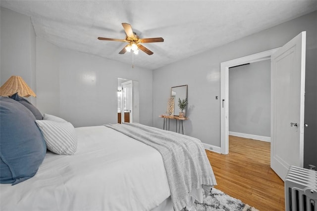 bedroom with ceiling fan, radiator heating unit, and hardwood / wood-style floors