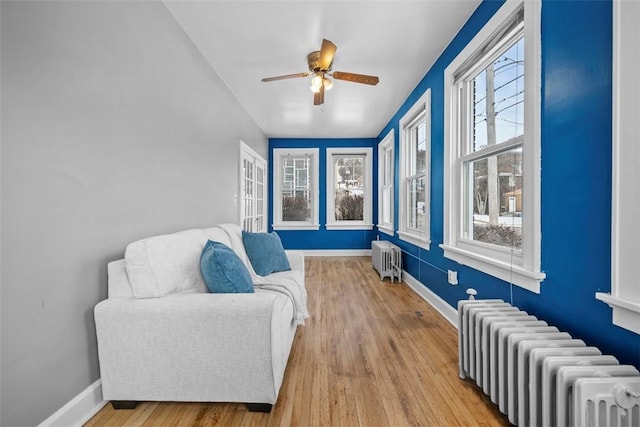 sitting room with wood-type flooring, radiator, and ceiling fan