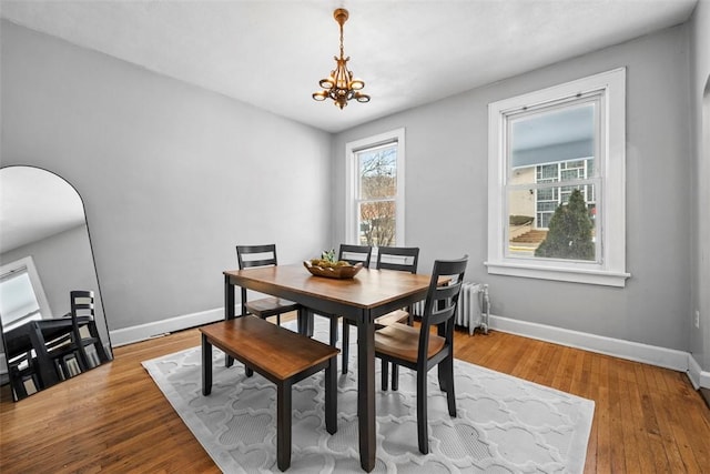 dining room with wood-type flooring, radiator, and a notable chandelier