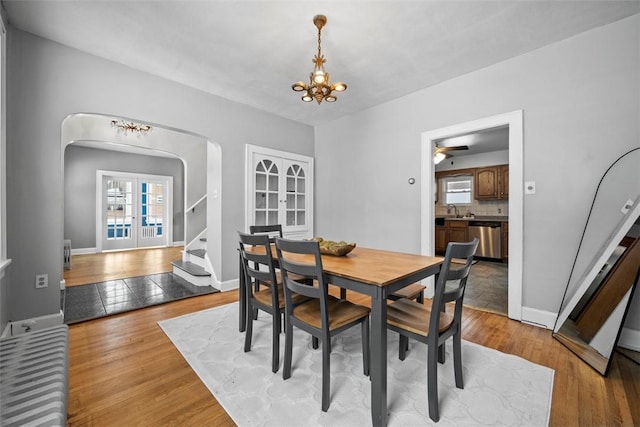 dining room with ceiling fan with notable chandelier, light hardwood / wood-style flooring, and sink