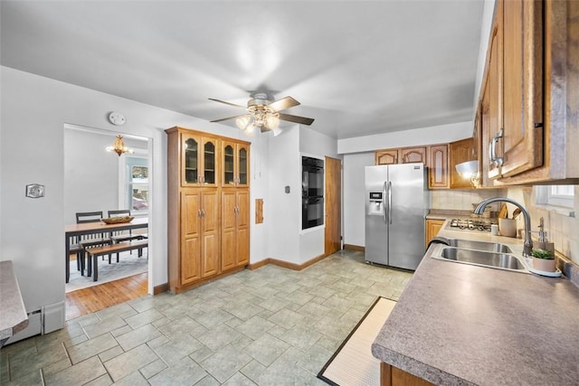 kitchen featuring backsplash, ceiling fan with notable chandelier, double oven, sink, and stainless steel fridge with ice dispenser