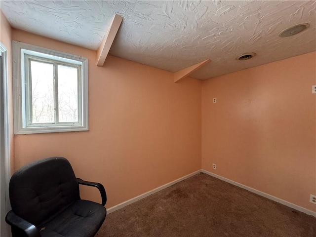 unfurnished room featuring beam ceiling, carpet floors, and a textured ceiling