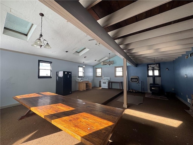 interior space with an inviting chandelier, a wood stove, and vaulted ceiling with skylight