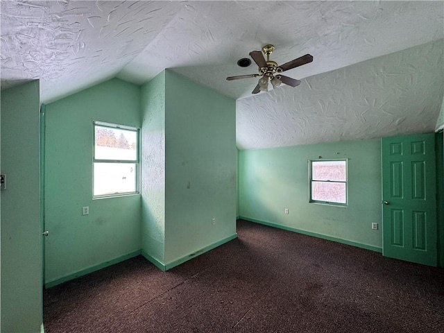 bonus room featuring ceiling fan, dark carpet, lofted ceiling, and a textured ceiling