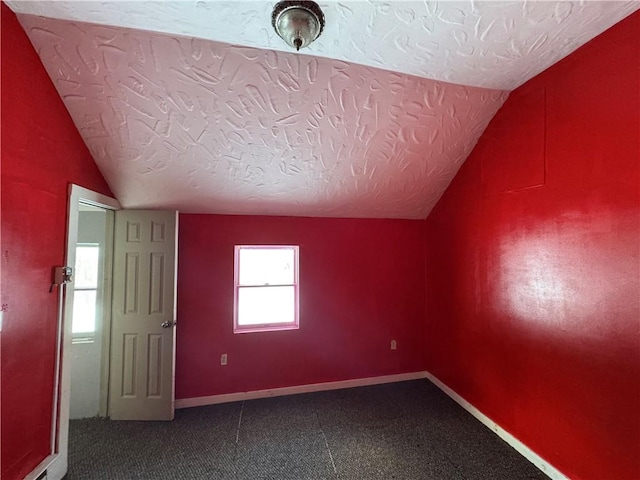 interior space with a textured ceiling and vaulted ceiling