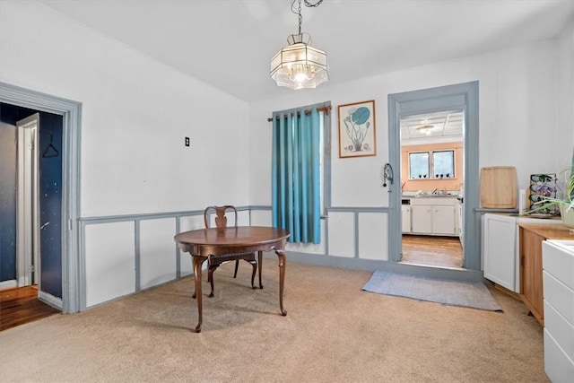 dining room with light carpet and a chandelier