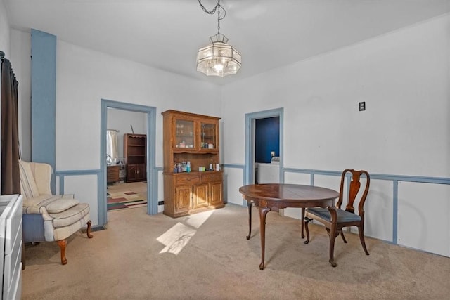 carpeted dining room featuring a chandelier