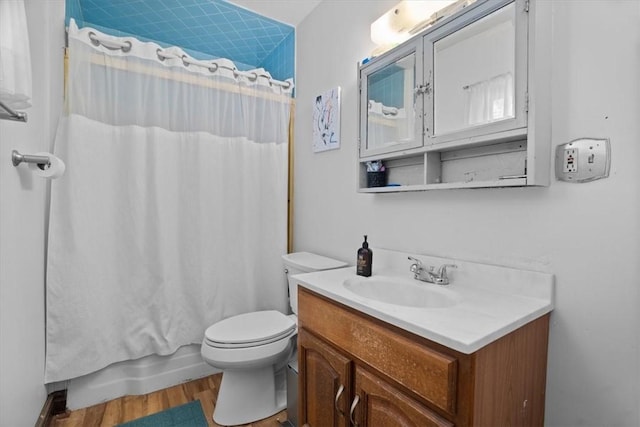 full bathroom with hardwood / wood-style floors, vanity, shower / tub combo, and toilet