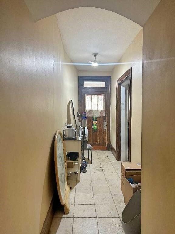 doorway with ceiling fan and light tile patterned floors