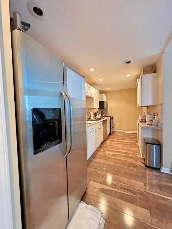 kitchen with white cabinets, stainless steel refrigerator with ice dispenser, light hardwood / wood-style flooring, and light stone countertops