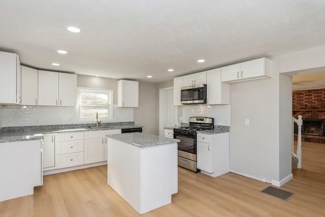 kitchen featuring sink, light hardwood / wood-style flooring, a kitchen island, white cabinetry, and stainless steel appliances