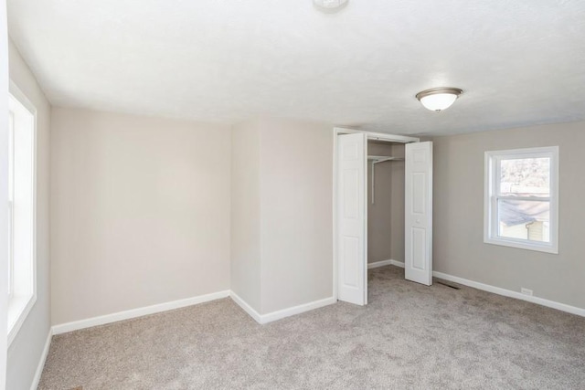 unfurnished bedroom with a closet and light colored carpet