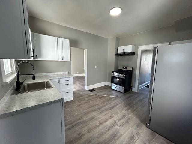 kitchen with white cabinets, sink, stainless steel appliances, and hardwood / wood-style flooring