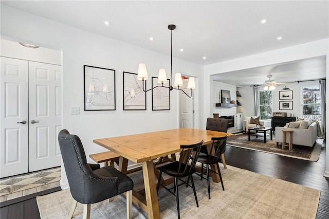 dining space with ceiling fan with notable chandelier and wood-type flooring