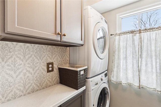 laundry area featuring cabinets and stacked washer / drying machine