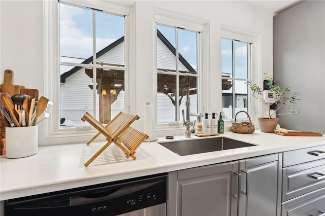 kitchen featuring stainless steel dishwasher, gray cabinets, and sink