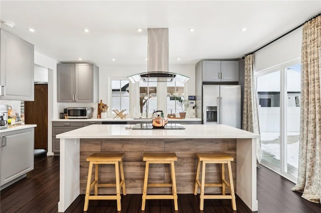 kitchen with stainless steel appliances, island range hood, dark wood-type flooring, a center island, and gray cabinets