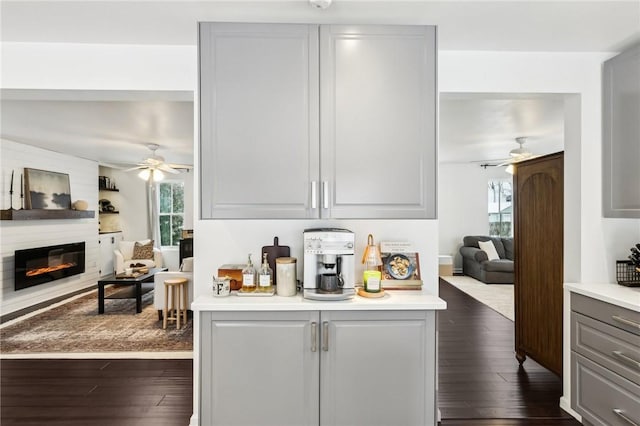 kitchen featuring gray cabinetry, ceiling fan, dark hardwood / wood-style flooring, and a fireplace