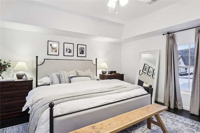 bedroom featuring a tray ceiling, ceiling fan, and dark wood-type flooring