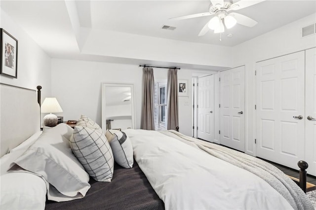 bedroom with ceiling fan and two closets