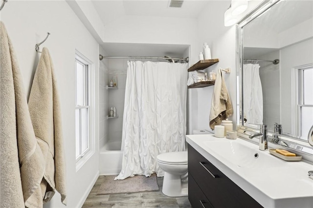 full bathroom with hardwood / wood-style flooring, vanity, shower / bath combination with curtain, and toilet