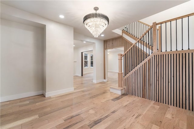 stairs featuring hardwood / wood-style floors and a notable chandelier