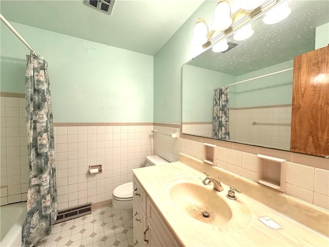 full bathroom with vanity, tile patterned flooring, toilet, tile walls, and shower / tub combo