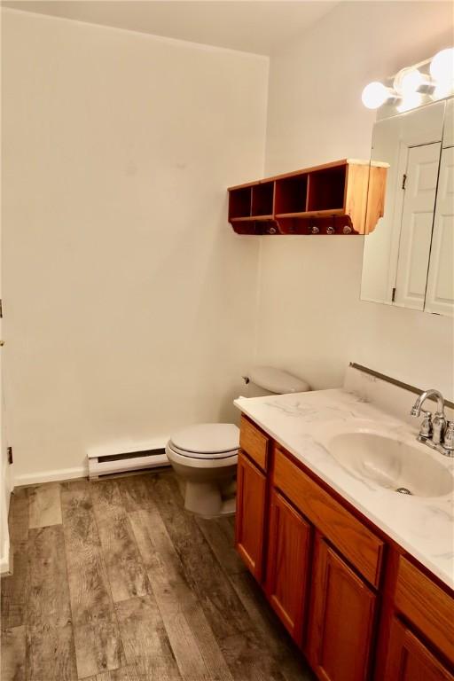 bathroom featuring hardwood / wood-style floors, vanity, toilet, and baseboard heating