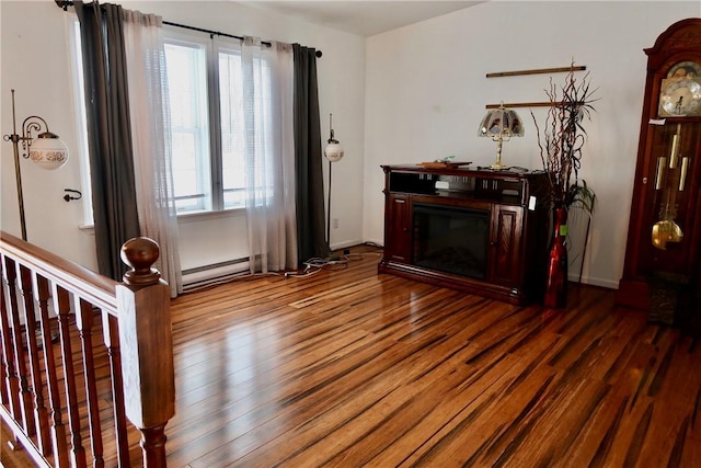 unfurnished living room featuring wood-type flooring and a baseboard radiator