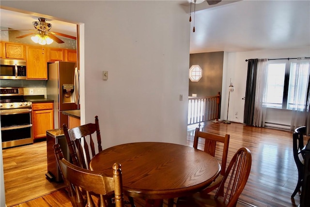 dining space featuring ceiling fan, light hardwood / wood-style floors, and a baseboard heating unit