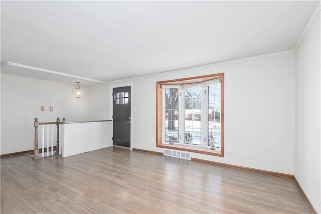unfurnished living room featuring visible vents, wood finished floors, and baseboards