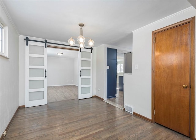 unfurnished dining area featuring a chandelier, a barn door, crown molding, and dark wood-type flooring