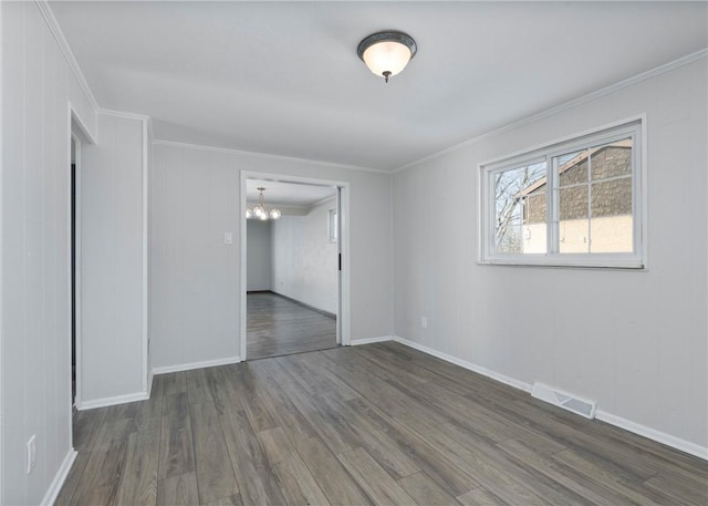empty room with dark wood finished floors, a chandelier, baseboards, visible vents, and crown molding