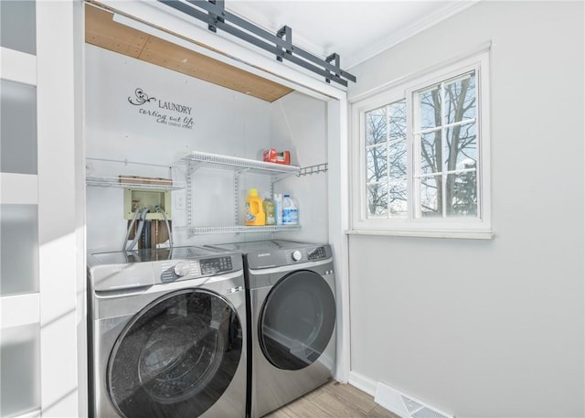 washroom featuring washing machine and dryer, laundry area, visible vents, baseboards, and wood finished floors