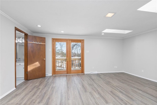 empty room with ornamental molding, a skylight, and light hardwood / wood-style floors