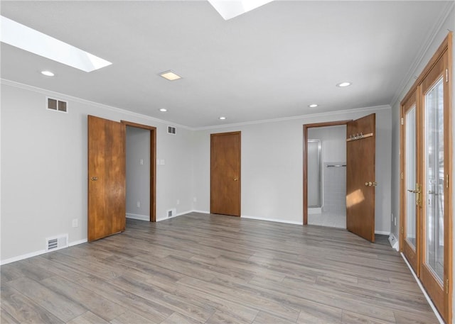 unfurnished bedroom featuring a skylight, light hardwood / wood-style flooring, and crown molding