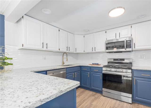 kitchen featuring appliances with stainless steel finishes, white cabinetry, blue cabinetry, and a sink