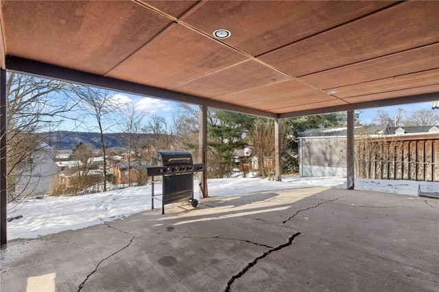 snow covered patio with a mountain view and a grill