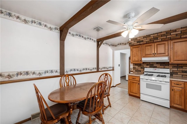 kitchen with light tile patterned floors, tasteful backsplash, ceiling fan, and gas range gas stove