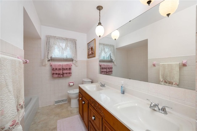 bathroom featuring tile patterned floors, vanity, toilet, and tile walls