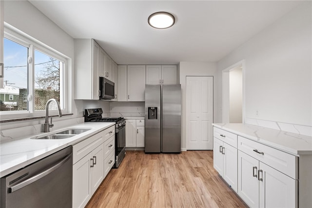 kitchen featuring white cabinets, light wood-type flooring, stainless steel appliances, and sink