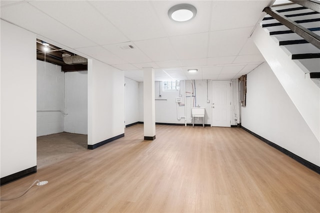 basement with a drop ceiling and wood-type flooring